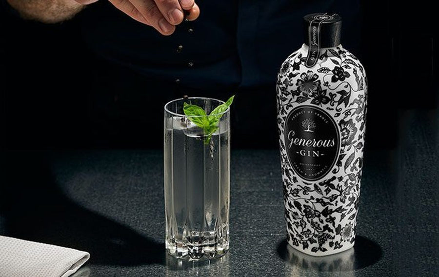 Bottle of Generous Gin beside a tall gin and tonic garnished with basil